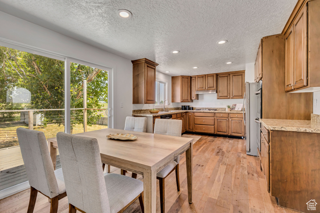 Dining room featuring light wood-type flooring, recessed lighting, and a textured ceiling
