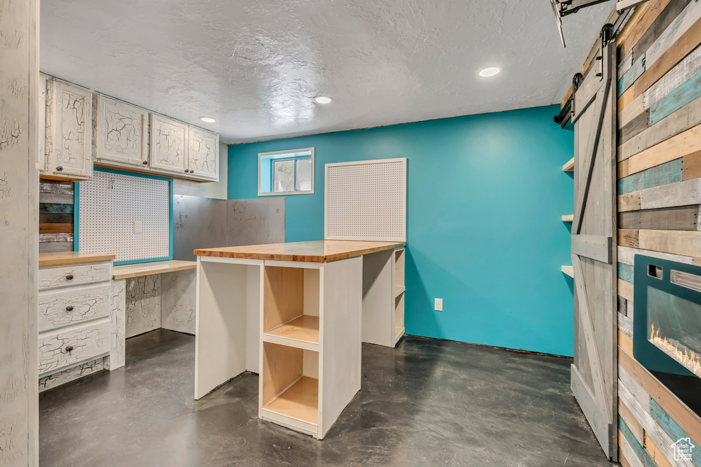 Misc room featuring a barn door, finished concrete floors, a textured ceiling, recessed lighting, and a workshop area
