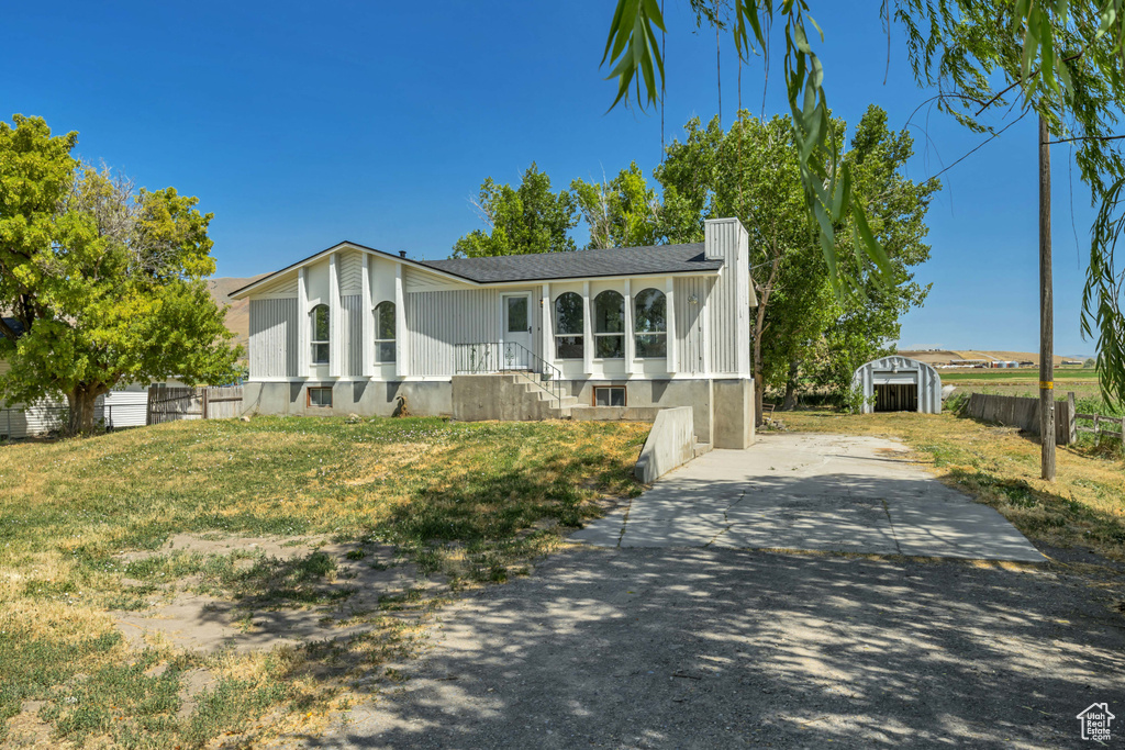View of front of house with a shed and a shingled roof