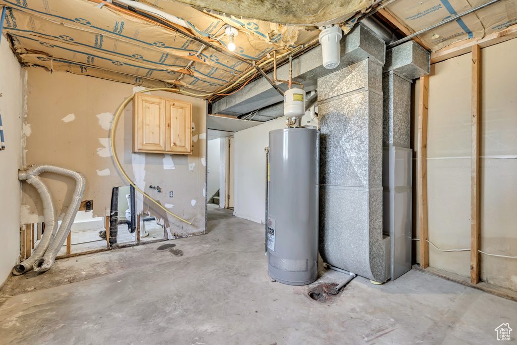 Unfinished below grade area with water heater, heating unit, and stairway