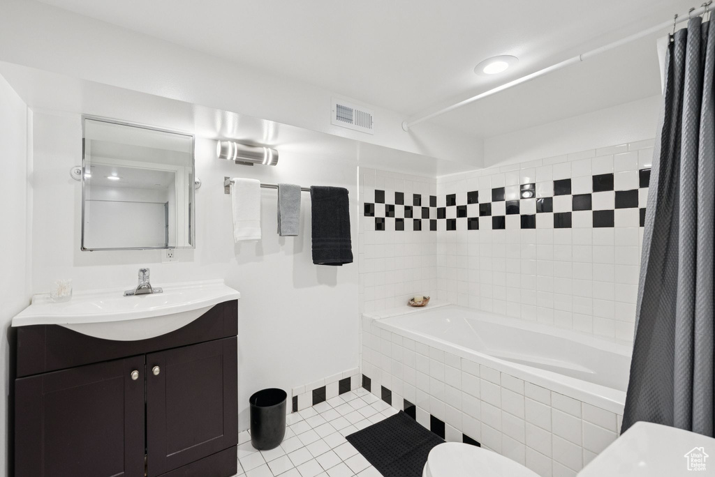 Bathroom featuring tiled shower / bath, tile patterned flooring, and vanity
