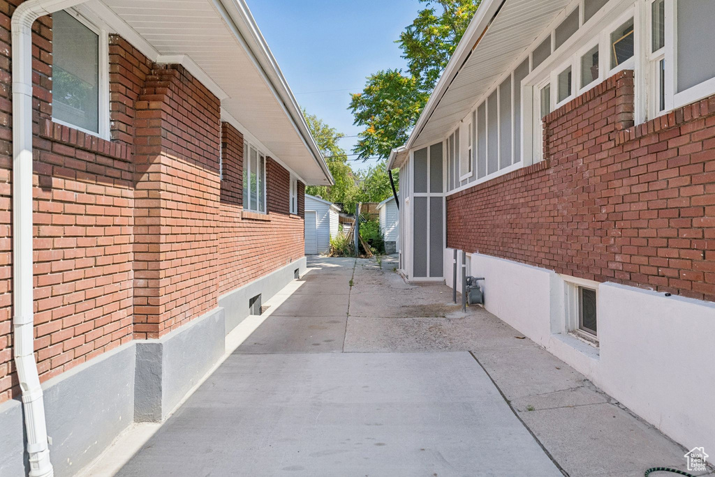 View of property exterior with brick siding and a patio area