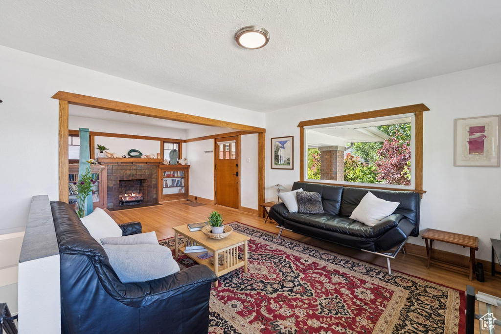 Living area featuring wood finished floors, a fireplace with flush hearth, and a textured ceiling