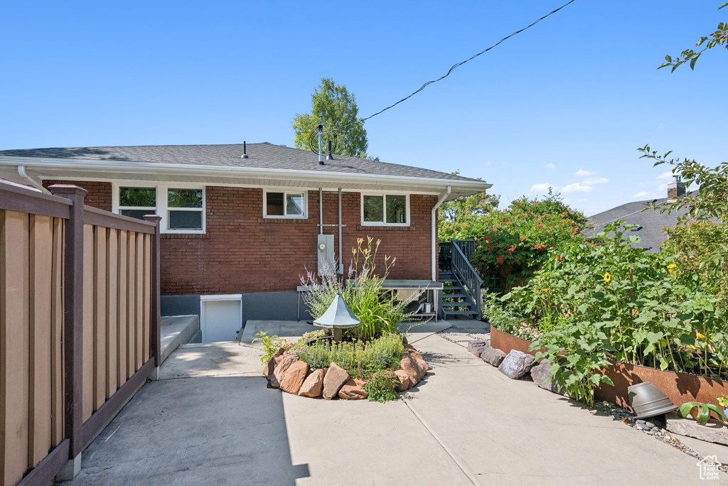 Rear view of property with a patio area, brick siding, and stairs