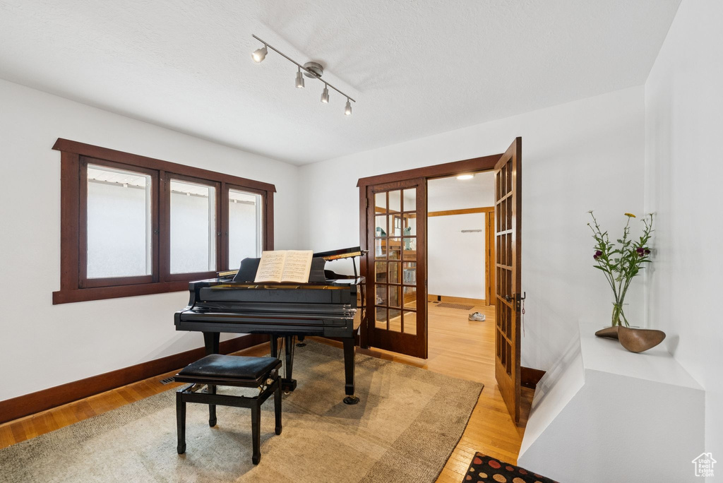 Living area with french doors, light wood finished floors, and track lighting