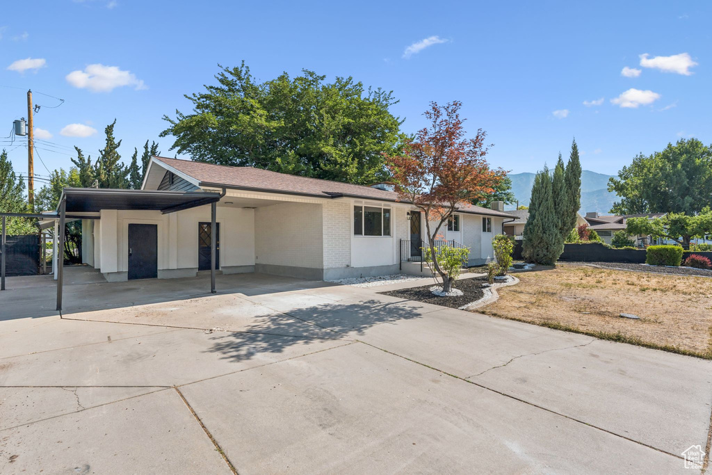 Ranch-style home with driveway, an attached carport, brick siding, and a mountain view