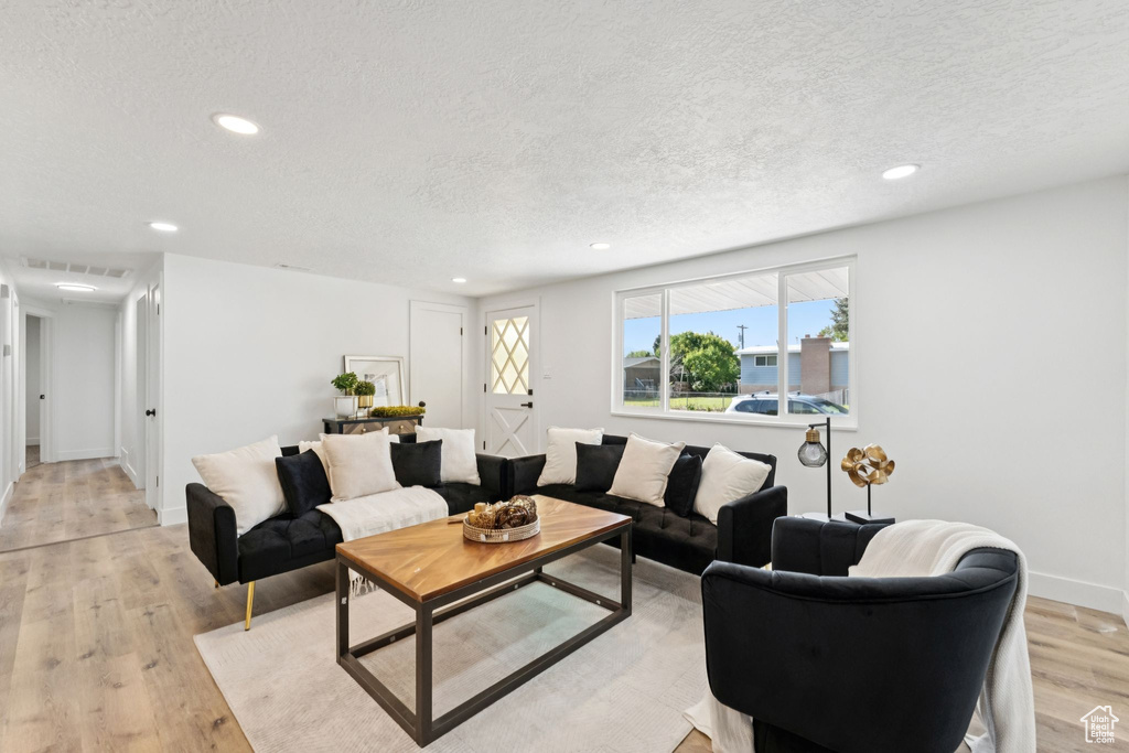 Living room featuring a textured ceiling, light wood finished floors, and recessed lighting
