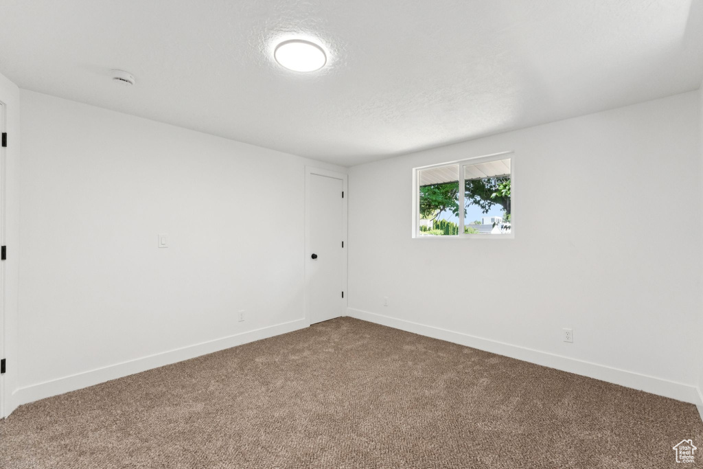 Carpeted spare room with a smoke detector and baseboards