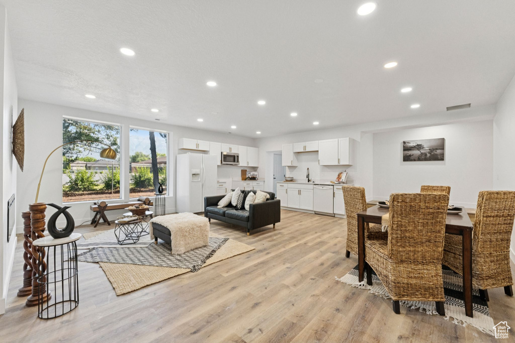 Dining room with light wood finished floors and recessed lighting