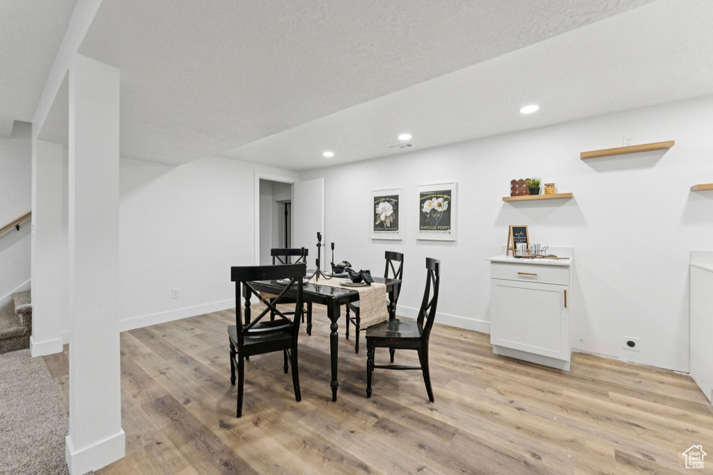 Dining room with light wood-style floors, recessed lighting, and stairway