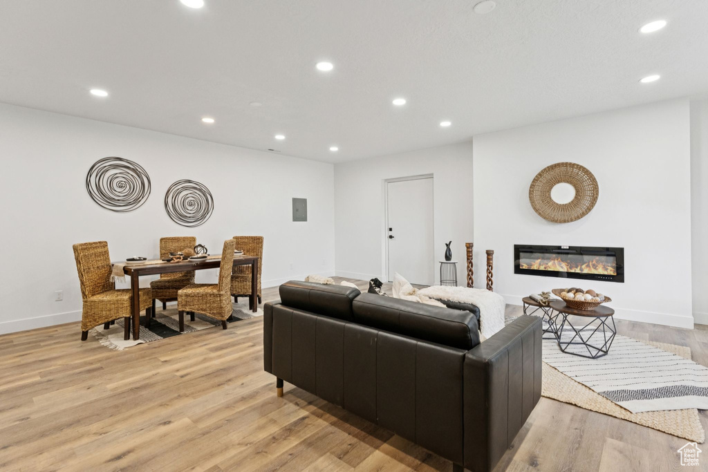 Living area featuring light wood-style floors, recessed lighting, and a glass covered fireplace
