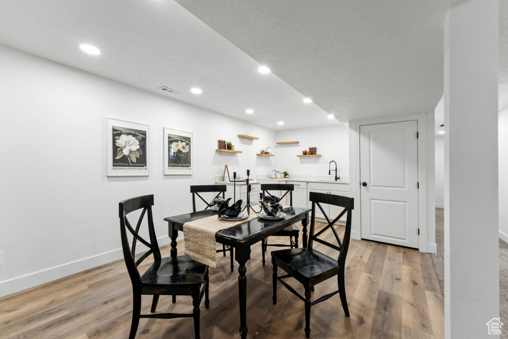 Dining space with light wood finished floors, recessed lighting, and wet bar