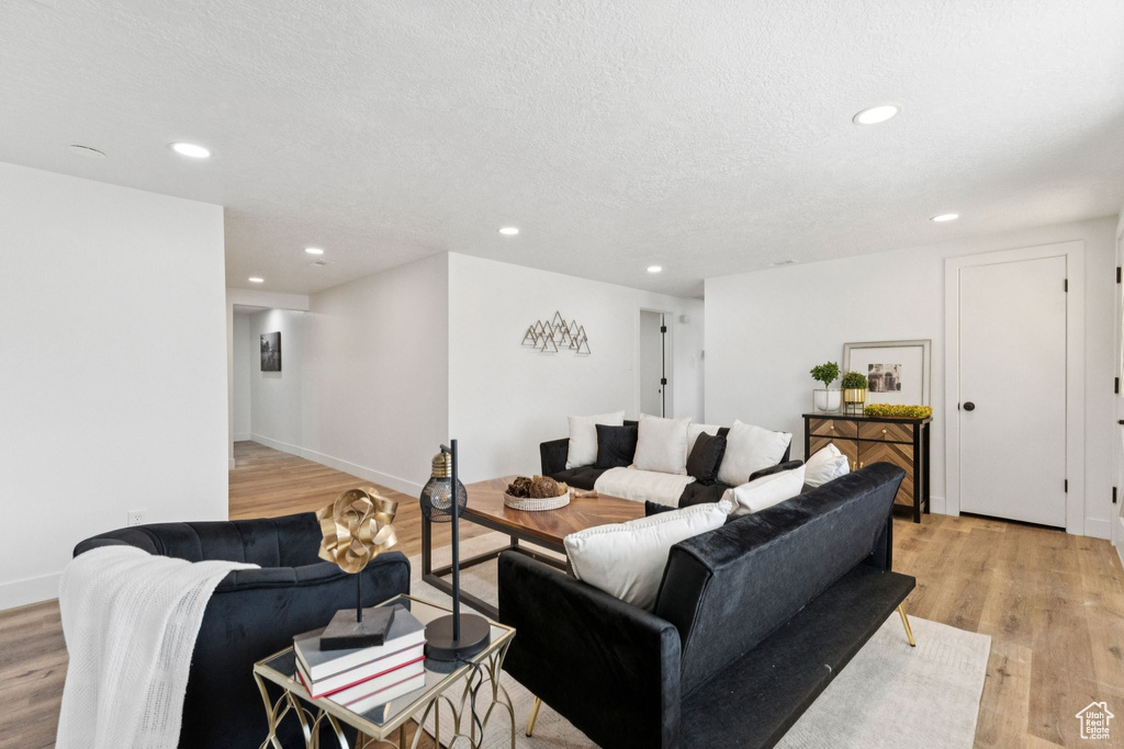 Living area with light wood-style floors, recessed lighting, and a textured ceiling