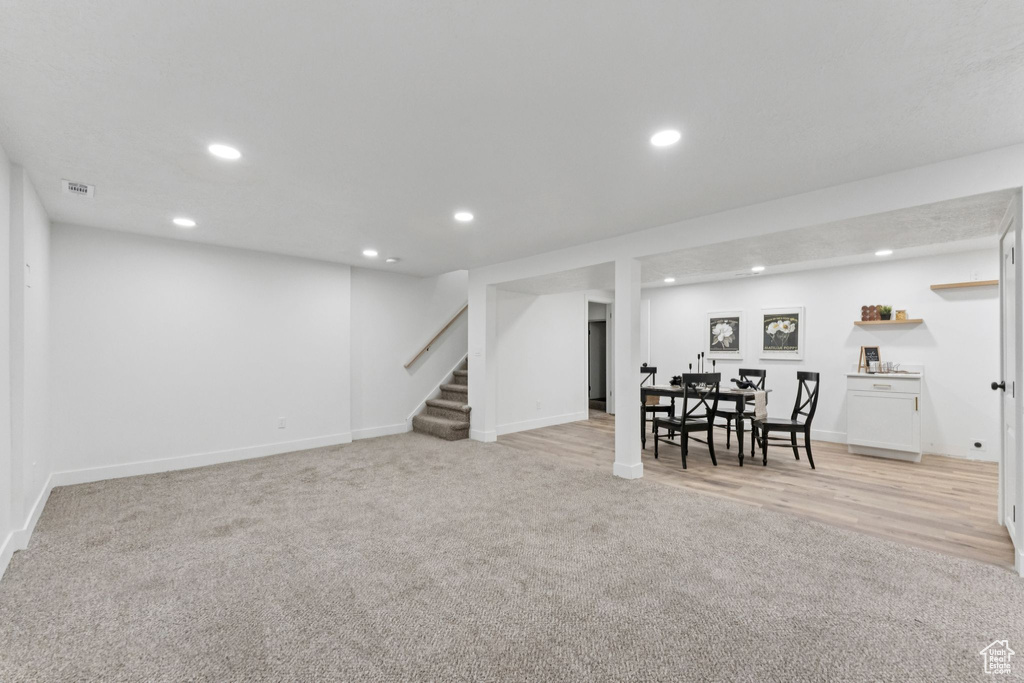Finished basement featuring light carpet, stairs, and recessed lighting