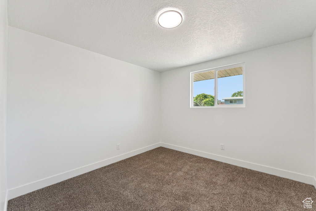 Unfurnished room featuring dark carpet and a textured ceiling