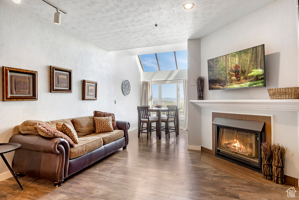 Living area featuring a tile fireplace, hardwood / wood-style flooring, and a textured ceiling