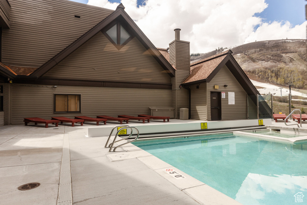 Community pool featuring a patio area, a mountain view, and a hot tub