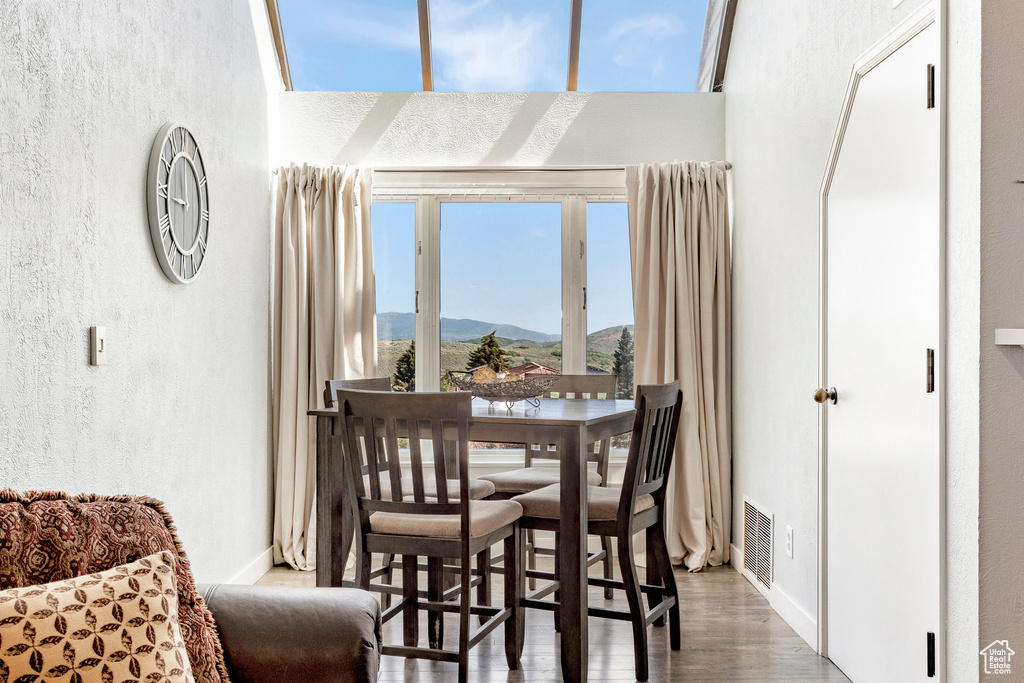 Dining area with wood finished floors, a textured wall, and a mountain view