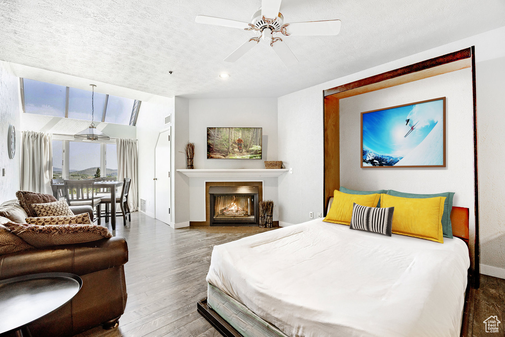 Bedroom featuring wood finished floors, access to exterior, a fireplace with flush hearth, a ceiling fan, and recessed lighting