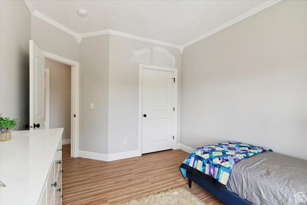Bedroom with crown molding and light wood-style floors