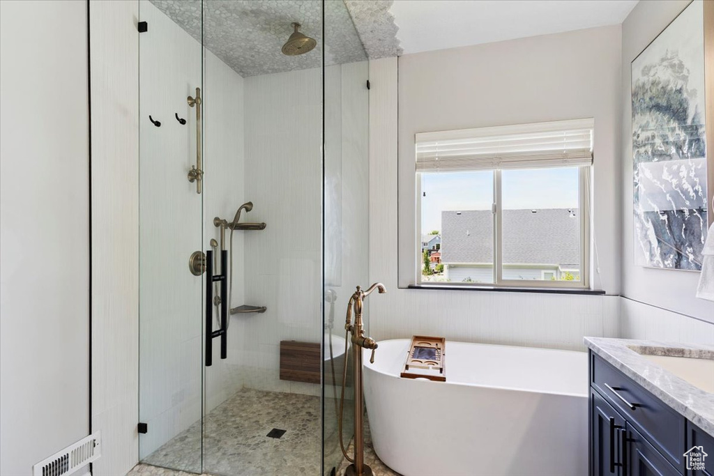 Bathroom with a shower stall, a freestanding tub, and vanity