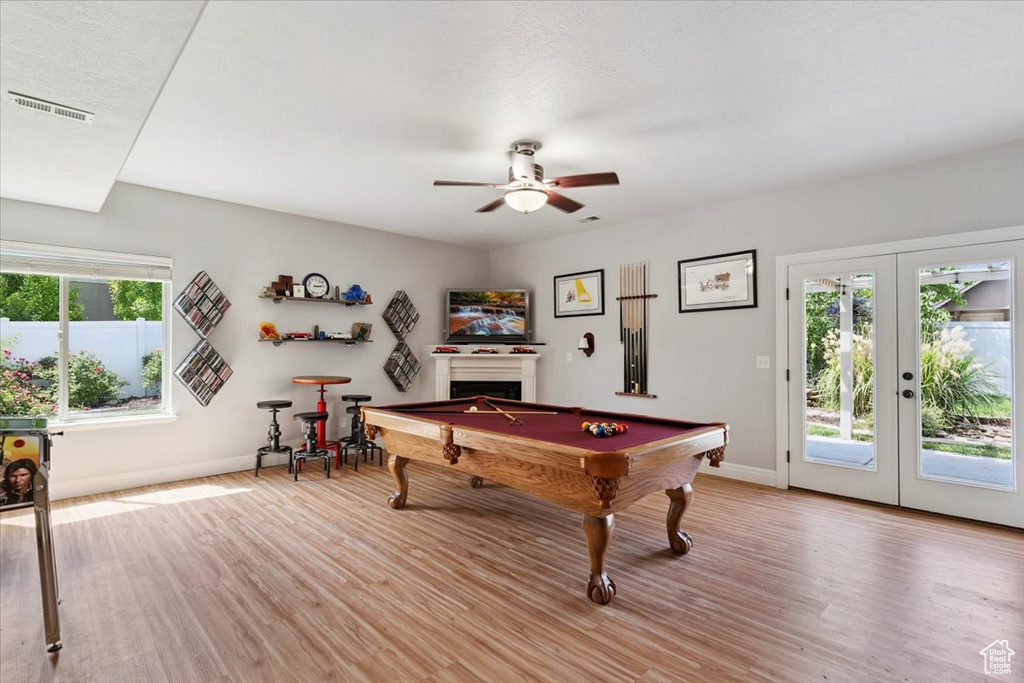 Playroom featuring pool table, light wood finished floors, a ceiling fan, french doors, and a fireplace