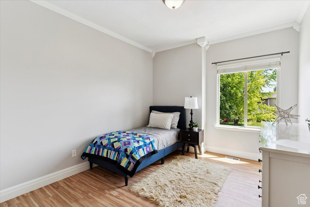 Bedroom featuring crown molding and wood finished floors