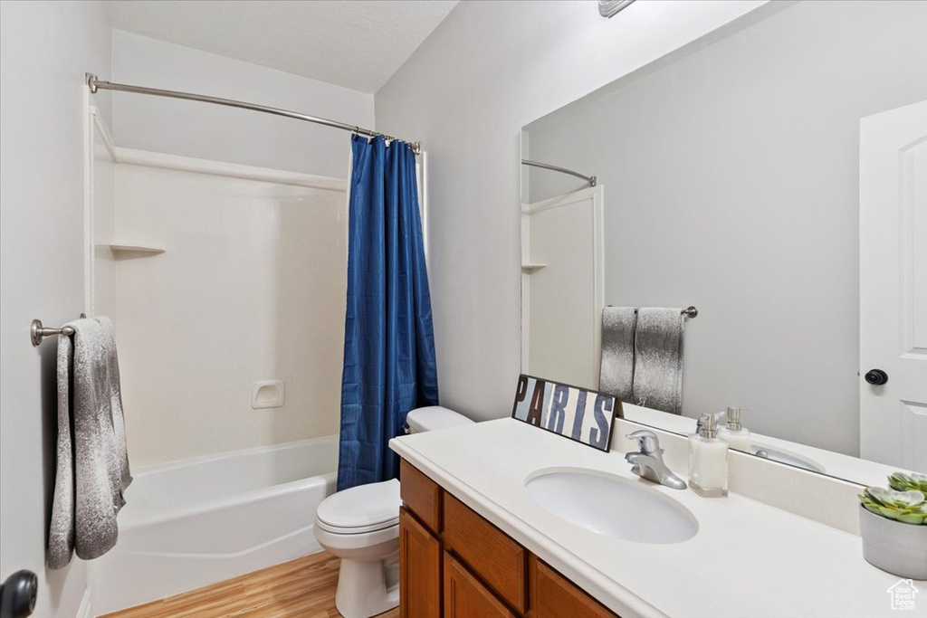 Bathroom featuring vanity, shower / bath combo, and wood finished floors