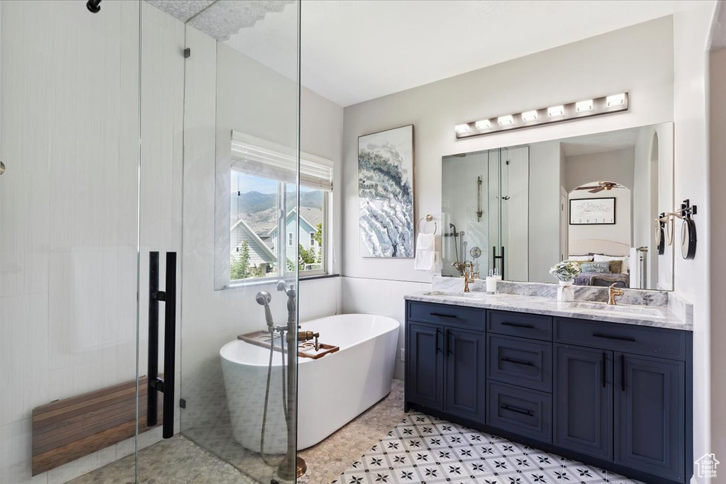 Full bathroom with double vanity, a shower stall, and a freestanding tub