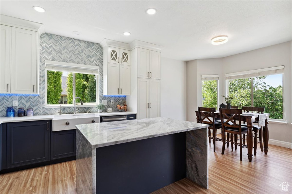 Kitchen featuring healthy amount of natural light, light wood-type flooring, decorative backsplash, and recessed lighting