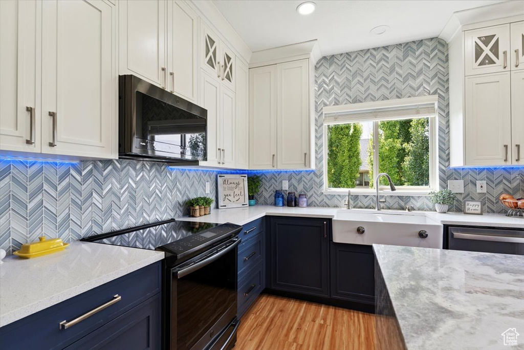 Kitchen with appliances with stainless steel finishes, blue cabinets, tasteful backsplash, white cabinetry, and recessed lighting