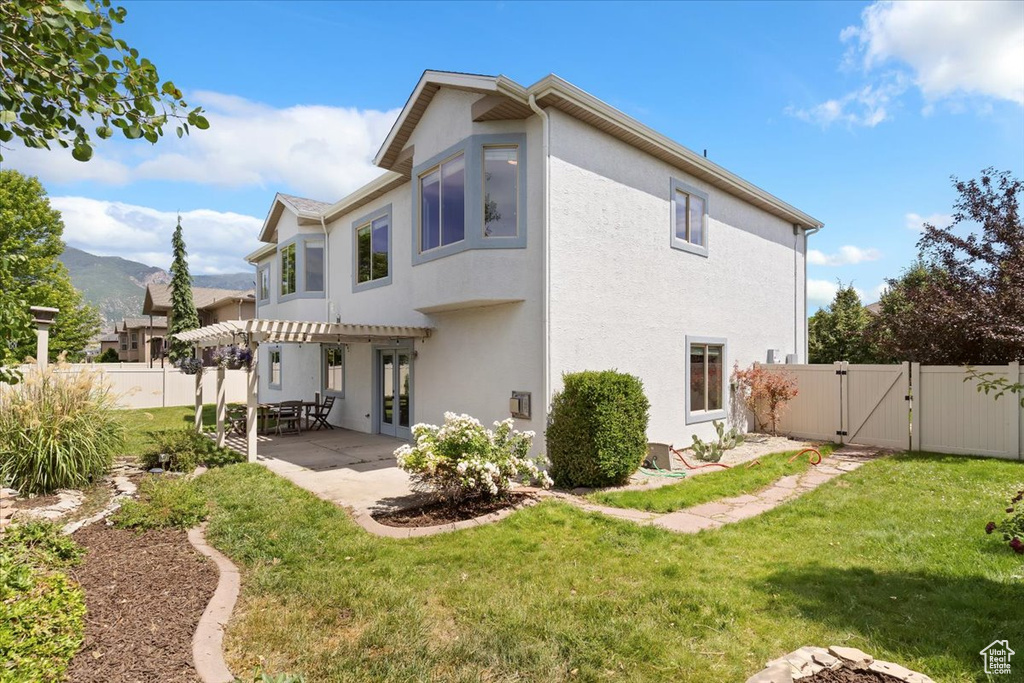 Rear view of house with a gate, stucco siding, a pergola, a fenced backyard, and a patio
