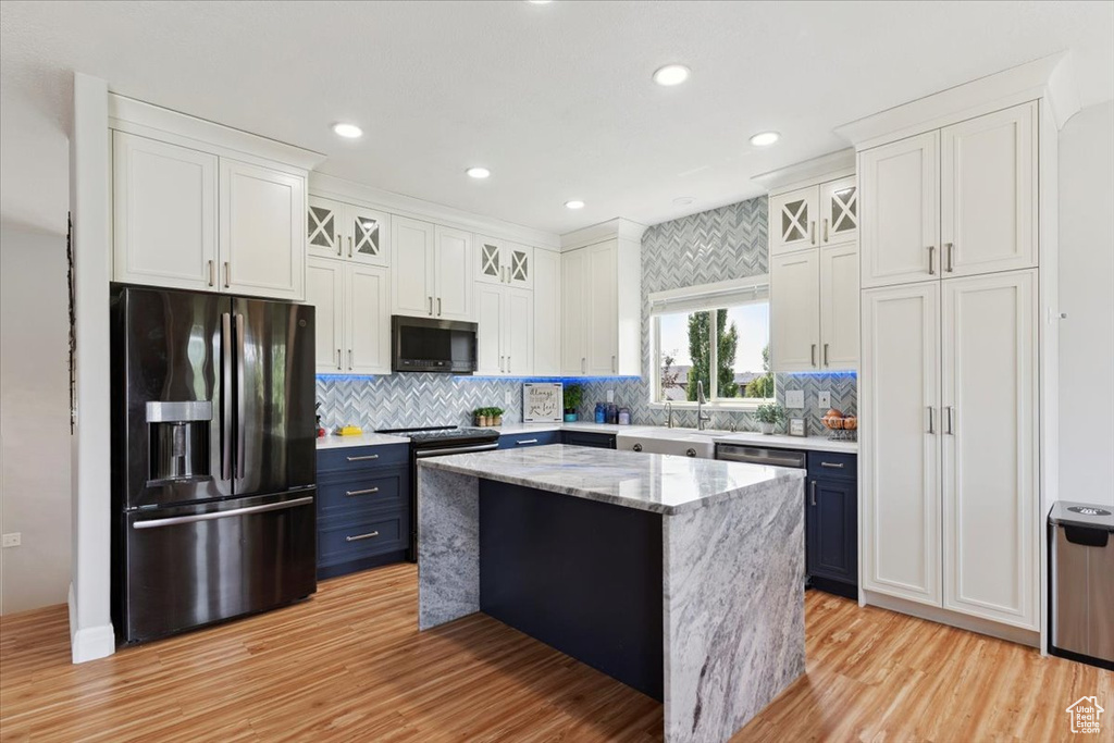 Kitchen featuring fridge with ice dispenser, blue cabinetry, light wood-style flooring, a center island, and white cabinets