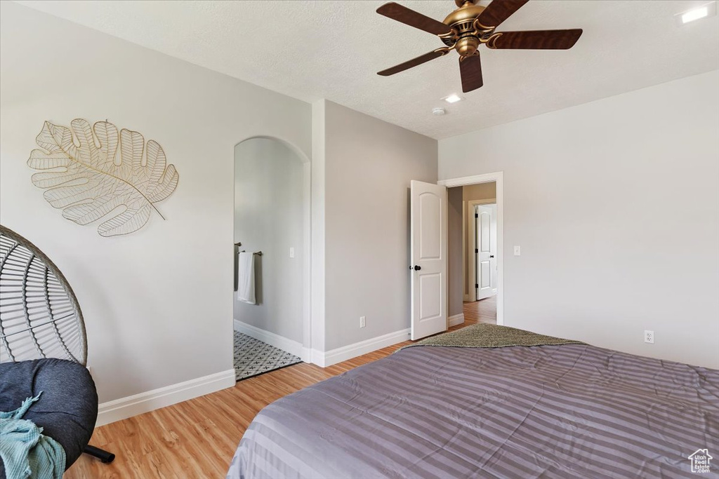 Bedroom featuring light wood-style flooring, ceiling fan, and arched walkways