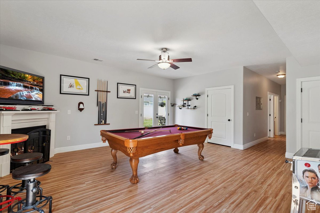 Game room featuring ceiling fan, light wood-style flooring, a fireplace, pool table, and french doors