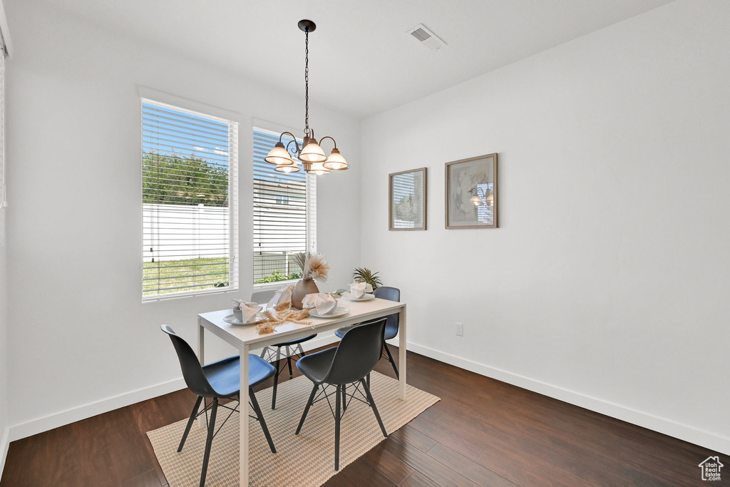Dining area with a chandelier and dark wood-style flooring