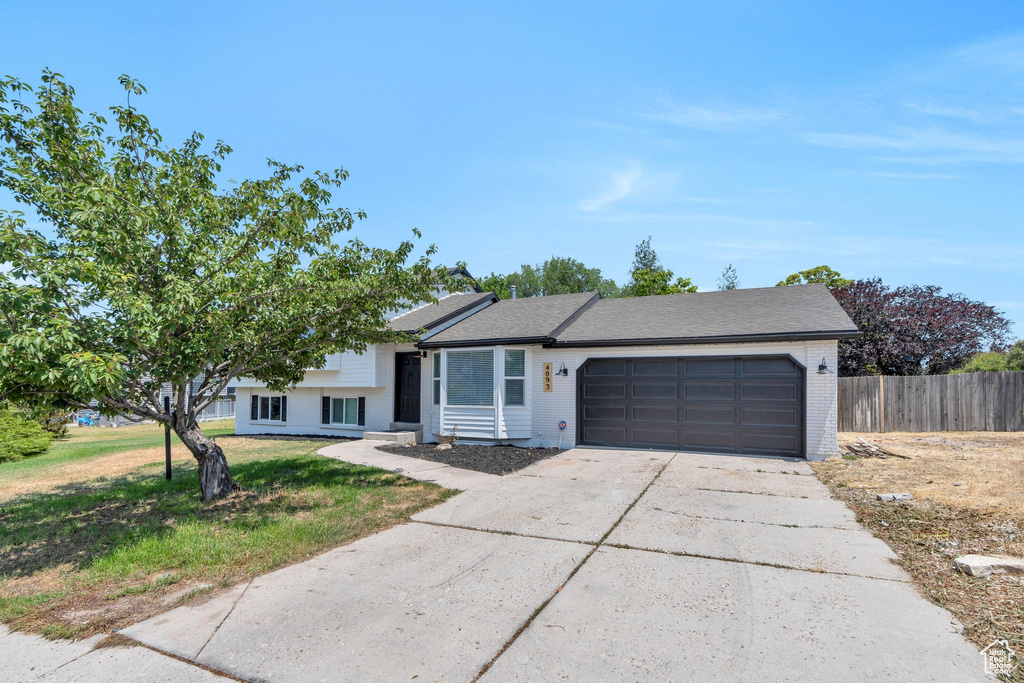 Split level home with an attached garage, driveway, and brick siding