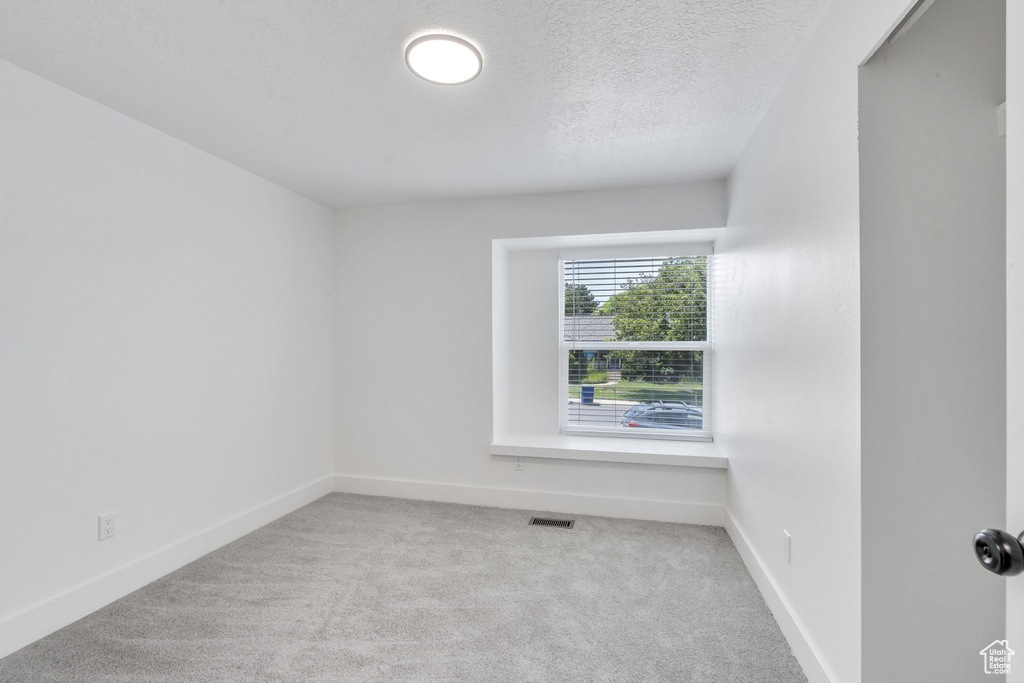 Carpeted empty room with baseboards and a textured ceiling
