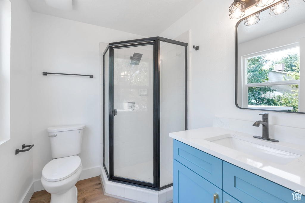 Full bath with vanity, a stall shower, and wood finished floors