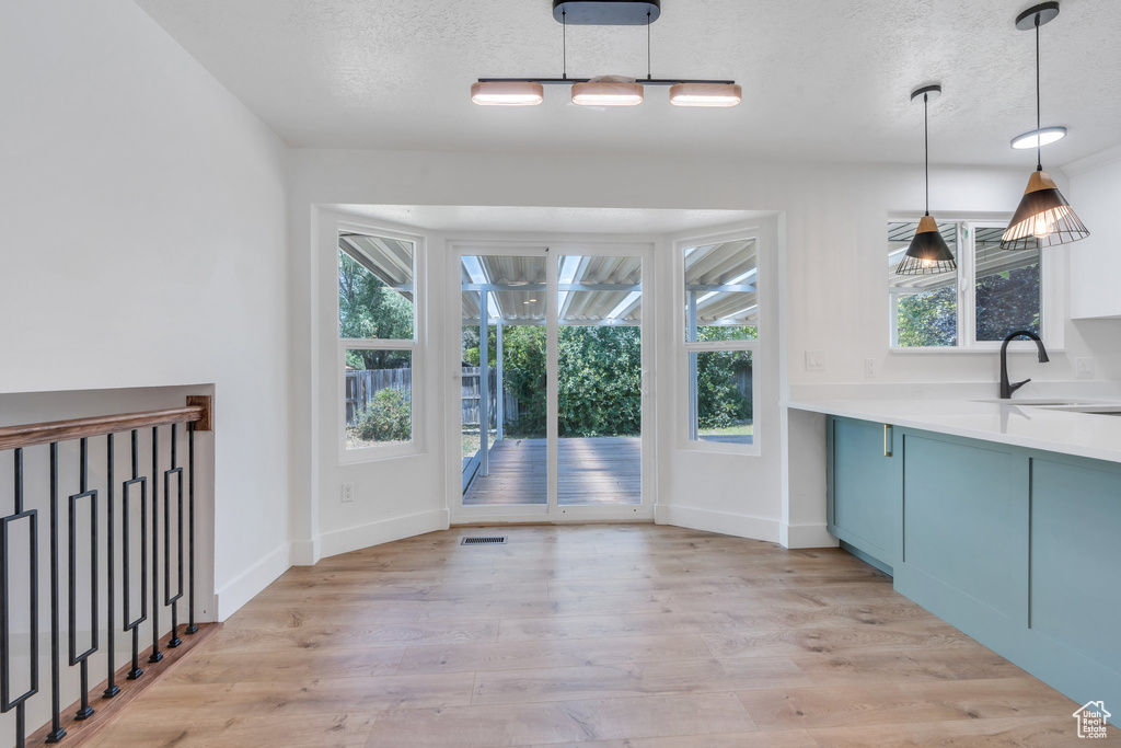 Unfurnished dining area featuring plenty of natural light, light wood-style floors, and a textured ceiling