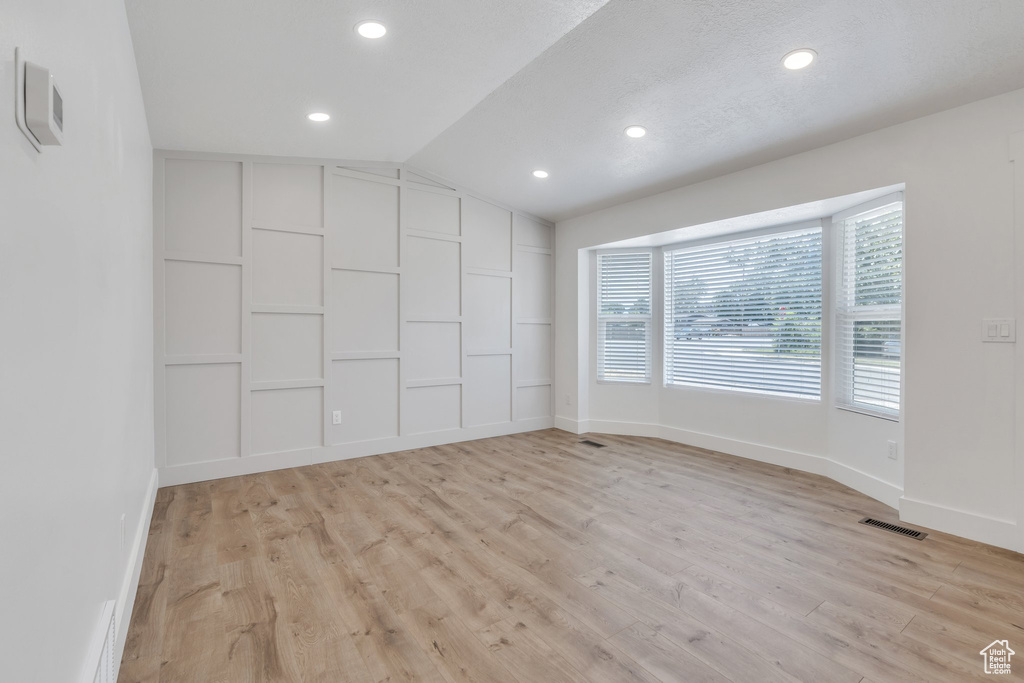 Spare room with vaulted ceiling, light wood-style floors, and recessed lighting