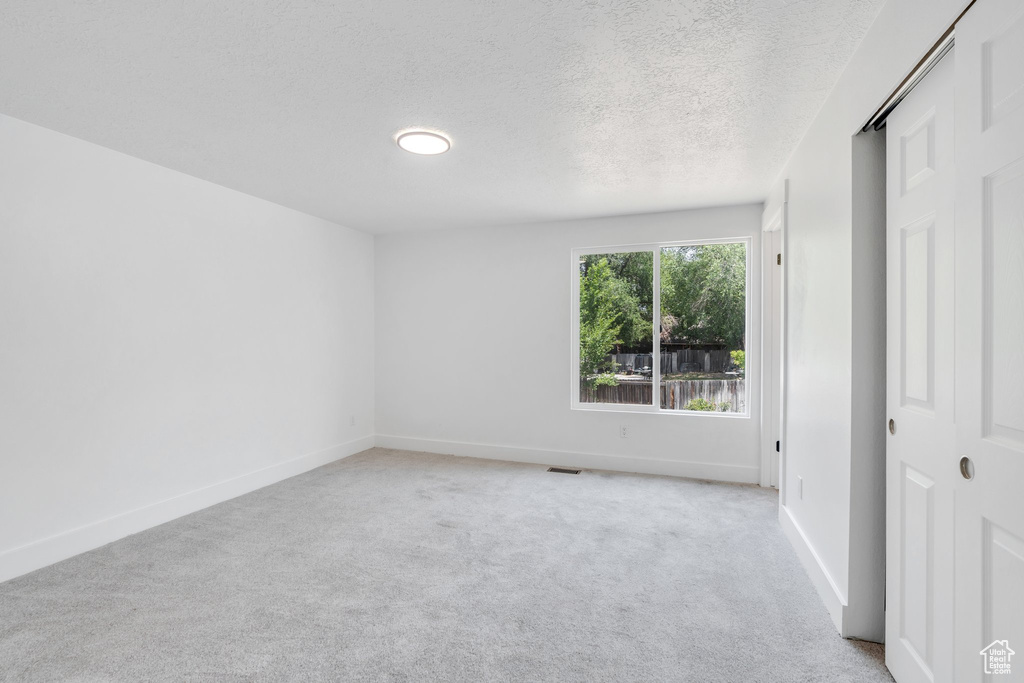 Spare room featuring light colored carpet and a textured ceiling