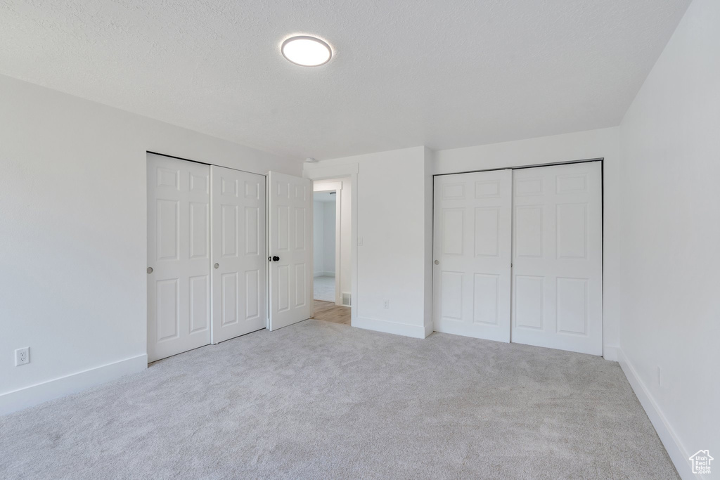 Unfurnished bedroom with two closets and carpet flooring
