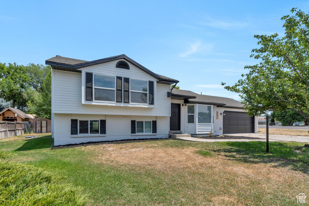 Tri-level home with brick siding, an attached garage, and concrete driveway