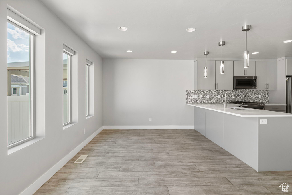Kitchen featuring appliances with stainless steel finishes, light countertops, recessed lighting, tasteful backsplash, and light wood-type flooring