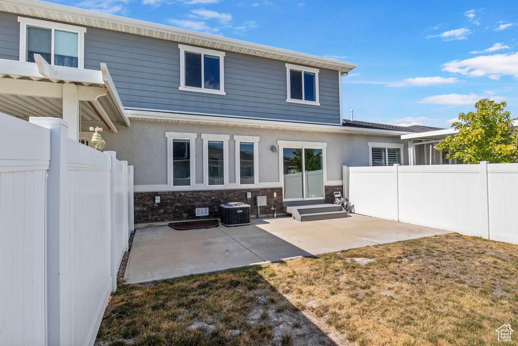 Rear view of house with a patio area, stone siding, and stucco siding