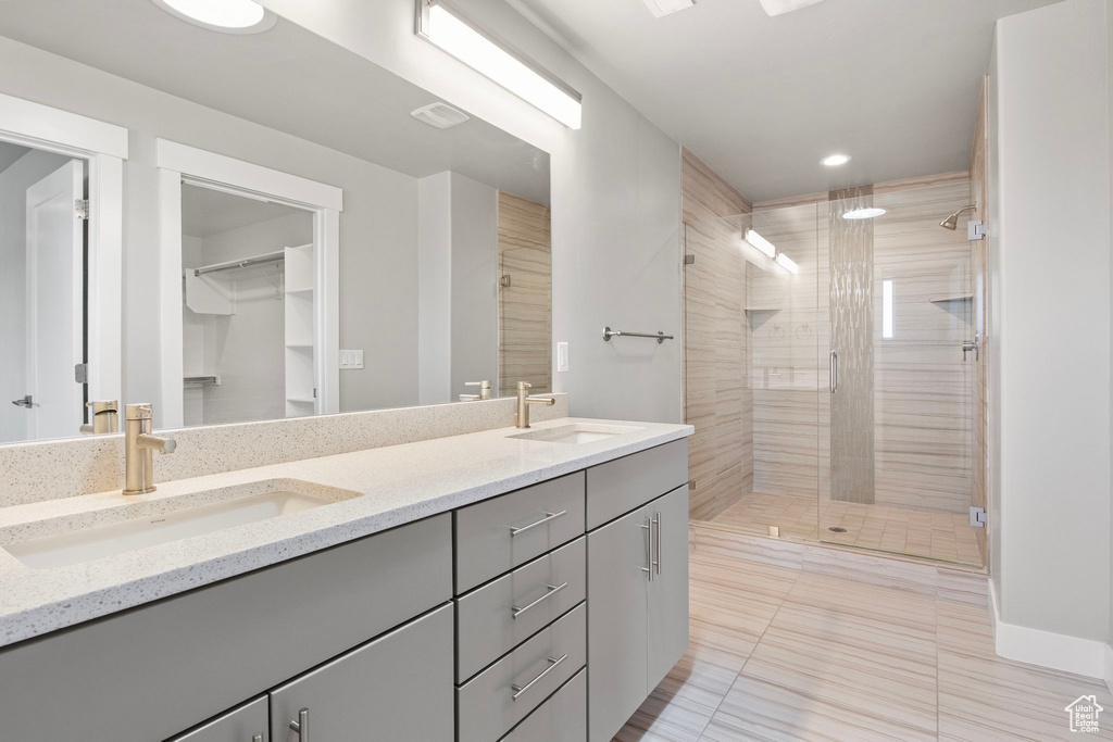 Full bathroom featuring double vanity, a stall shower, a spacious closet, tile patterned floors, and recessed lighting