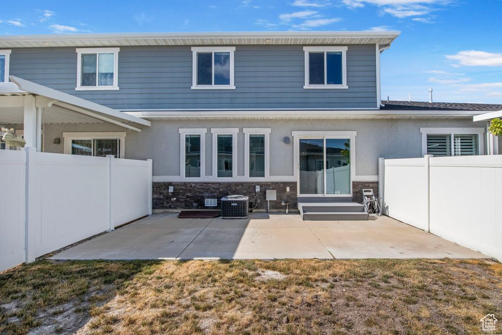 Rear view of property featuring stone siding and a patio area