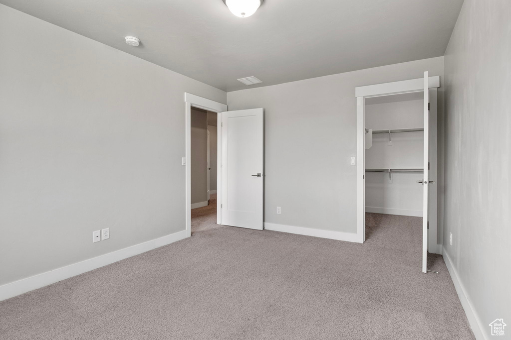 Unfurnished bedroom featuring carpet floors, a spacious closet, and a closet