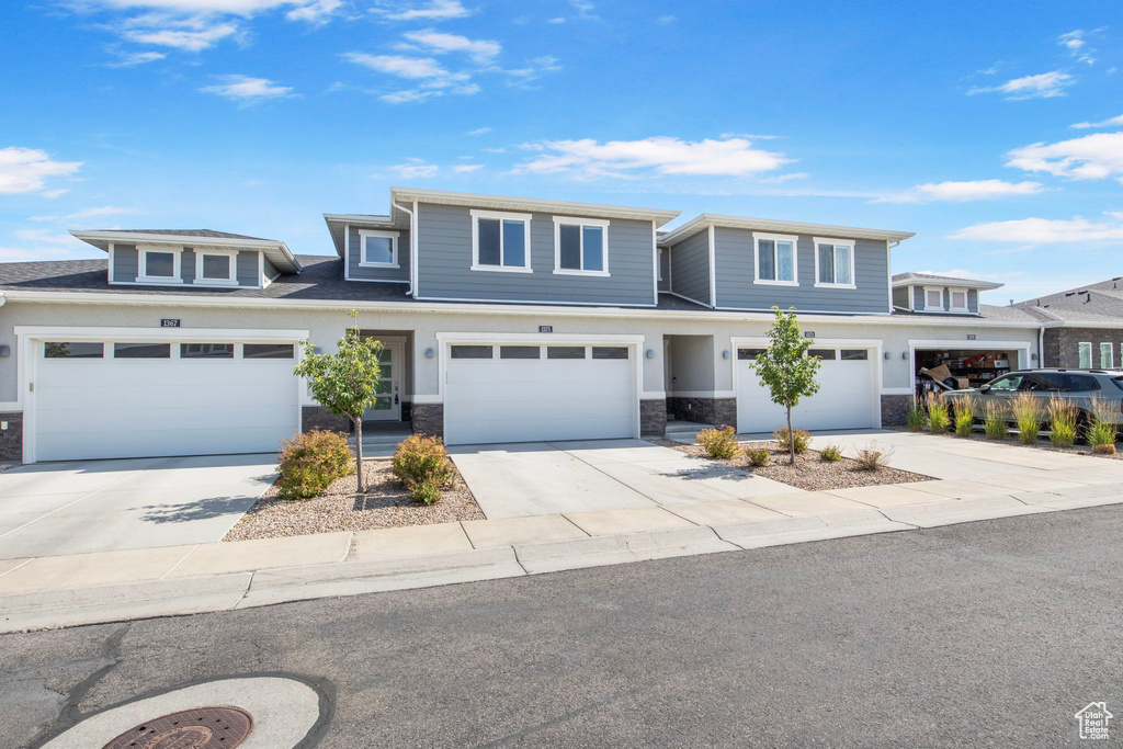 View of front of property with driveway, stone siding, and an attached garage